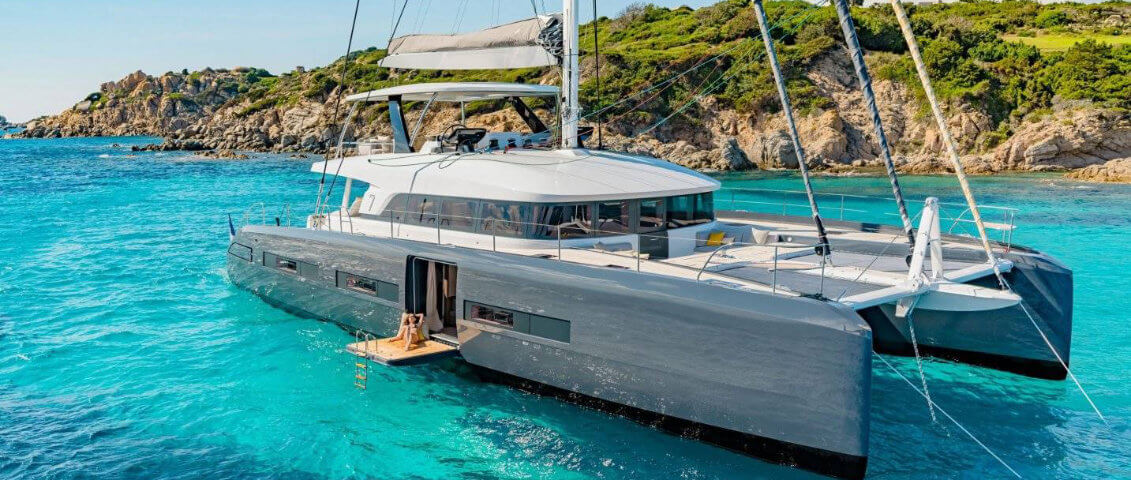 	Photo en plongée d'un catamaran luxueux privatisé où une personne bronze et une autre nage à côté
